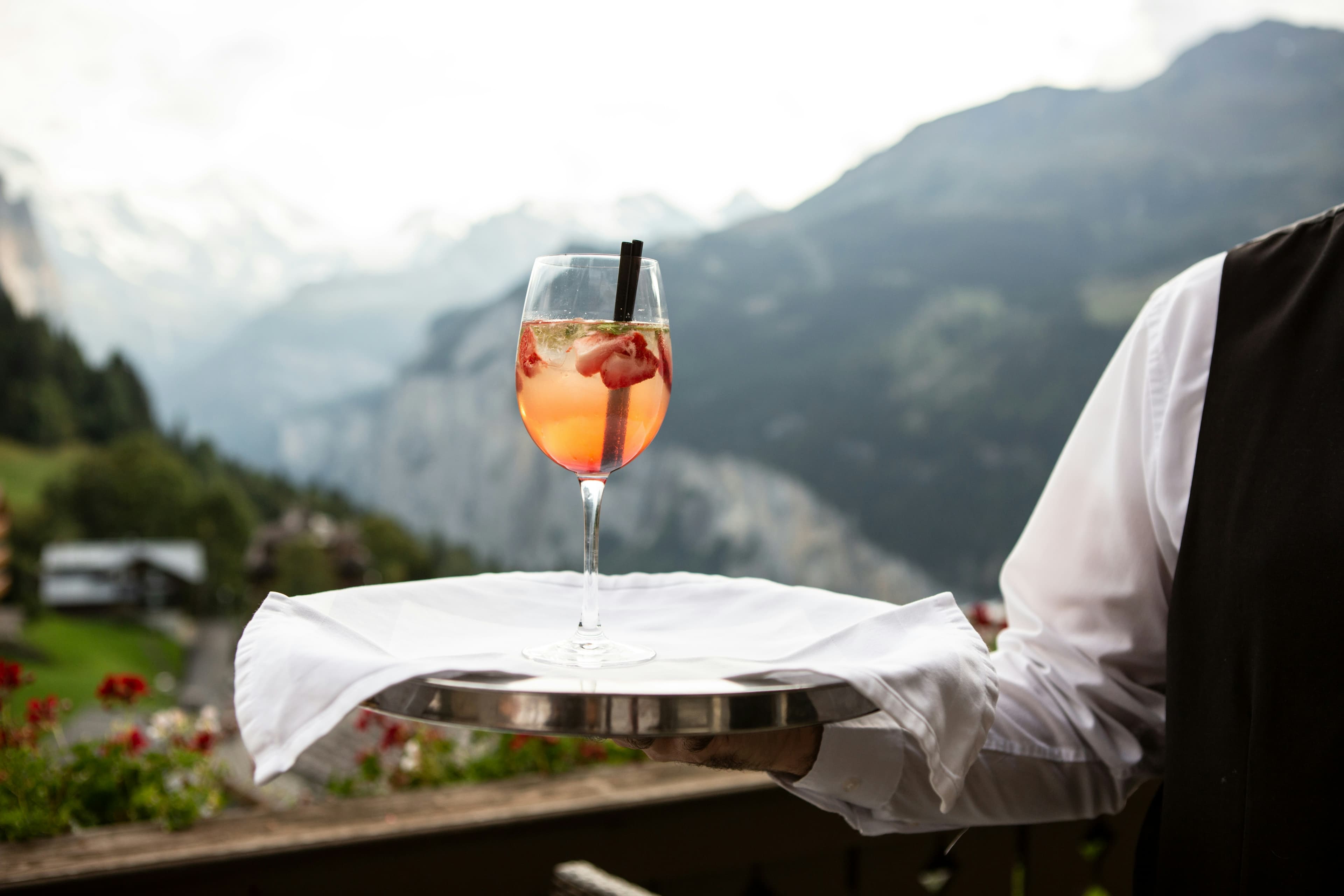 Champagne glass served by waiter on a table in the background of a mountain landscape
